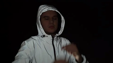 Handsome happy guy dancing on black background in reflective jacket Stock Footage 150787589