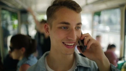 Handsome happy guy with perfect teeth talks on phone in tram Stock Footage 113798631