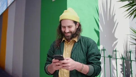 Handsome happy man standing in a corner and chatting with friends using Stock Footage 108427501