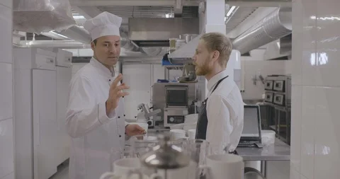 Handsome head chef talking to young inexperienced waiter Stock Footage 125050973