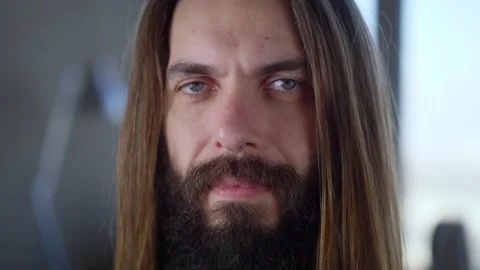 Handsome hipster bearded long haired young man portrait indoors, looking at Stock Footage 148901826