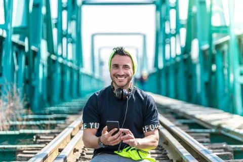 Handsome Hipster Guy Using the Cellphone and Wearing Headphones. Sitting on t Stock Photos