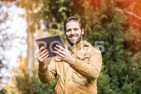 Handsome hipster man posing for the camera with a tablet. graded with a flare Stock Photos