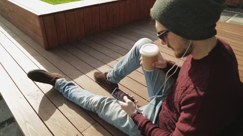 Handsome hipster using app and listening to music in smartphone headphones Stock-Footage 68398802