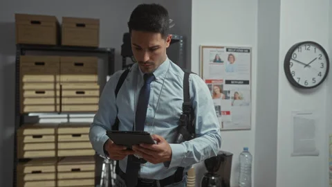 Handsome hispanic detective with beard in office scrutinizes digital tablet.. Stock Footage 274704716