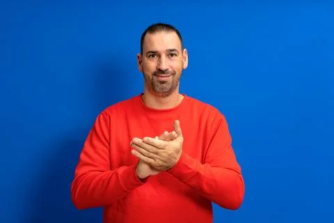 Handsome hispanic man with a beard in a red jumper clapping his hands in co.. Stock Photos