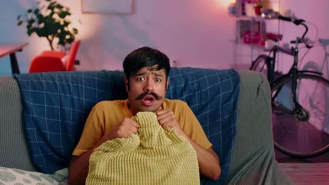 Handsome Hispanic man getting scared of horror movie watching alone at couch Video stock 117131605