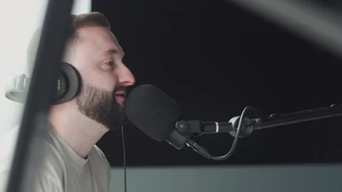 Handsome hispanic man speaks into a microphone while recording a radio show in h Stockbeeldmateriaal 240681969