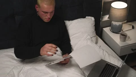 Handsome homosexual man working with Documents using laptop on Bed before going Stock-Footage 146907102