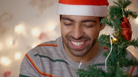 Handsome Indian boy / man blows a confetti from hands near Christmas tree 스톡 동영상 111273809
