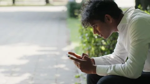 Handsome Indian entrepreneur analyze data on smartphone while sitting in Stock Footage 218444426