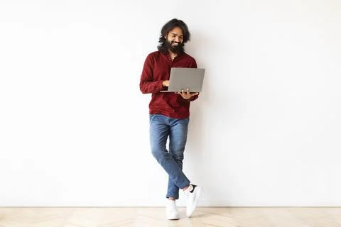Handsome indian guy using laptop computer on white 写真素材