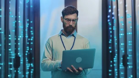 Handsome IT server engineer holding laptop wearing glasses ID badge standing in Stock Footage 119233115