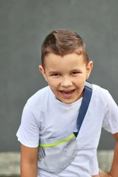 A handsome little boy is posing for the camera, smiling. Carefree childhood. Stock Photos