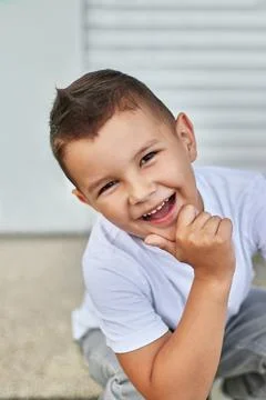 A handsome little boy is posing for the camera, smiling. Carefree childhood. Stock Photos