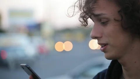 Handsome long haired man shooting video message on telephone outdoors, close-up Stock Footage 97645899