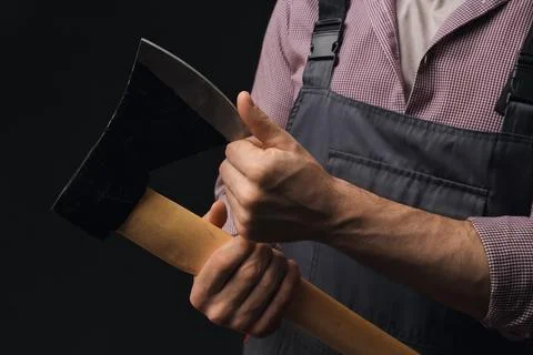 Handsome lumberjack with sharp ax on dark background, closeup Stock Photos