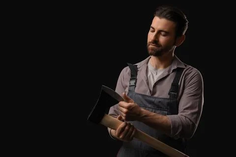 Handsome lumberjack with sharp ax on dark background Stock Photos