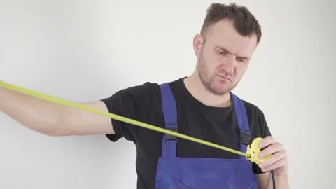 A handsome male builder in uniform pulls out of his pocket and looks at his Stock Footage 154988802
