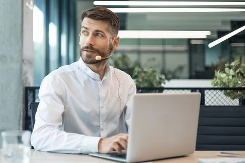 Handsome male customer support operator consulting clients with headset and l Stock Photos