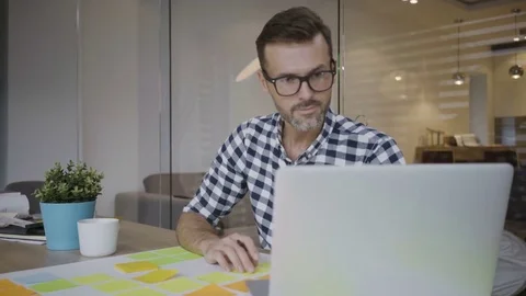 Handsome male developer working with laptop and notes and then drinking coffe Stock Footage 79801186
