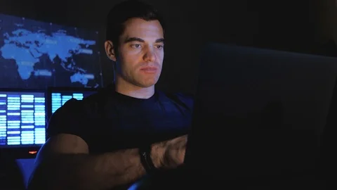 Handsome male hacker programmer works at a computer at night in a data center Stock Footage 102923258