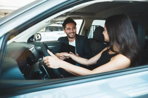 Handsome man and young beautiful woman checking new car interior while sitting Stock Photos