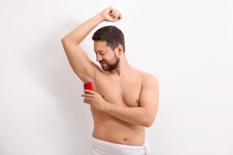 Handsome man applying solid deodorant on white background Stockfoto's