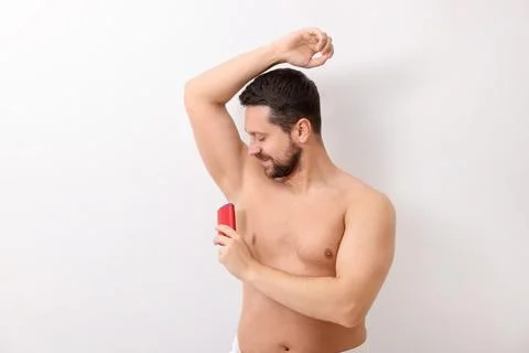 Handsome man applying solid deodorant on white background Stockfoto's