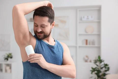 Handsome man applying solid deodorant at home. Space for text 스톡 사진