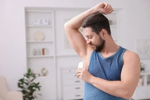 Handsome man applying solid deodorant at home. Space for text Stockfoto's