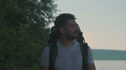 The handsome man with backpack walking along the coast. slow motion Stock Footage 159732546