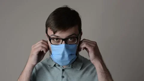Handsome man with beard and glasses takes off protective mask Stock Footage 154650763