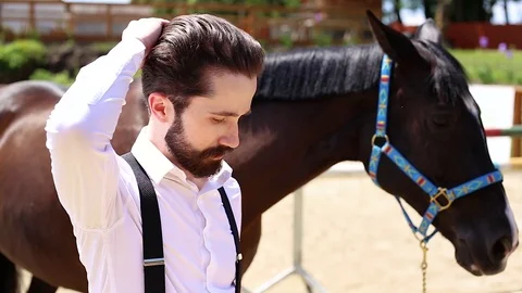 Handsome man with beard and mustache standing by the horse Stock Footage 118012944