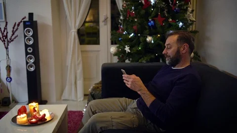 Handsome man with a beard answering his mobile phone with a Christmas tree on Video stock 78552157
