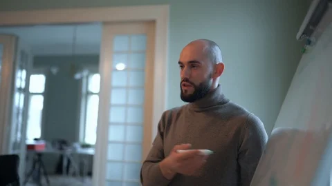 Handsome man with beard discusses strategy with a team, draws on a flipchart 스톡 동영상 124717425
