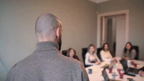 Handsome man with beard discusses strategy with a team, draws on a flipchart 스톡 동영상 124717857