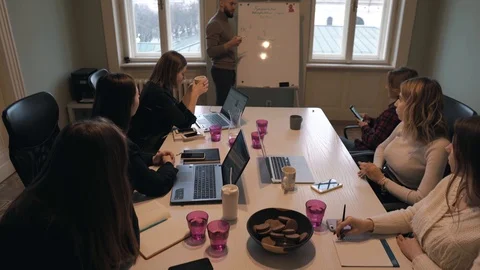 Handsome man with beard discusses strategy with a team, draws on a flipchart 스톡 동영상 124717923
