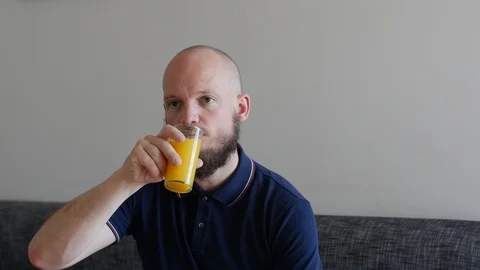 Handsome Man with beard drinking fresh Orange juice and disgusted by pulp. Funny Stock Footage 112030999