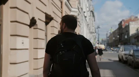 Handsome man with a beard exploring a city, wearing black backpack, looking Video stock 68027715