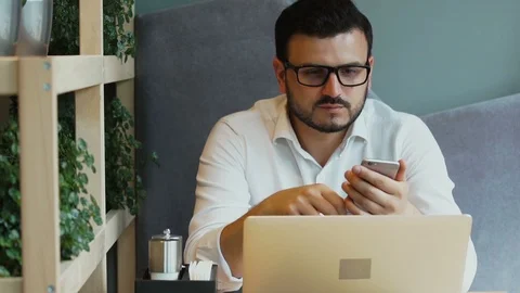 Handsome man with beard freelancing in cafe and using his phone Video stock 112988910