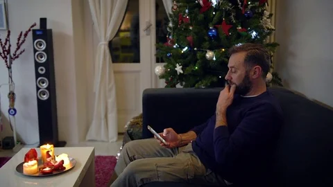 Handsome man with a beard interacting with his mobile phone with a Christmas  動画素材 79919054