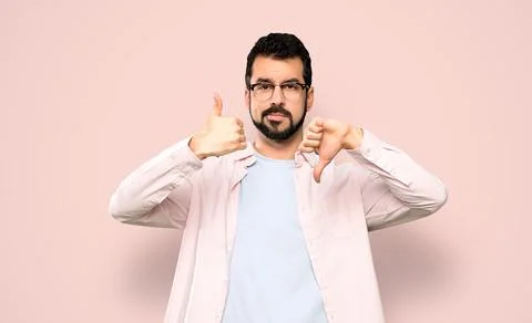Handsome man with beard making good-bad sign. Undecided between yes or not Stock Photos