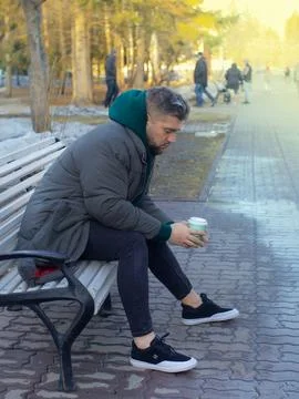 Handsome man with beard man drinks coffee take away in a park in spring Фото
