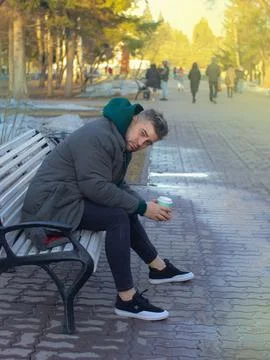 Handsome man with beard man drinks coffee take away in a park in spring 스톡 사진