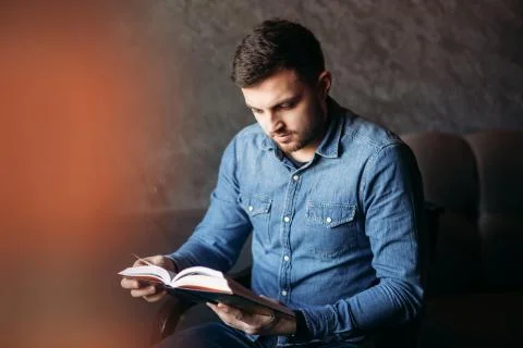 Handsome man with a beard reading a book in a cafe Stock Photos