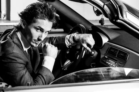 Handsome man with beard in suit driving car Stock Photos