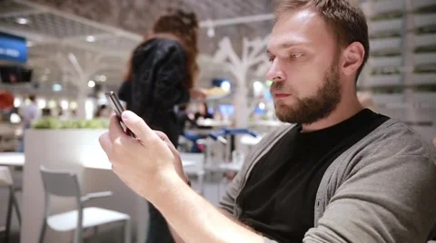 Handsome man with a beard using his smartphone in a cafe. Modern technology Stock Footage 67947501