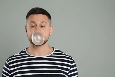 Handsome man blowing bubble gum on light grey background, space for text Stock Photos