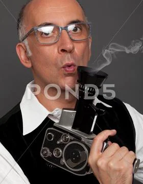 Handsome man blowing smoke off film camera Stock Photos